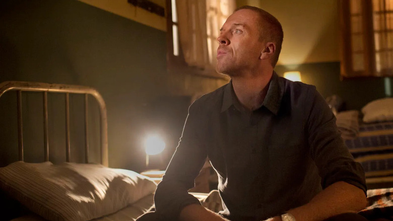 Nicholas Brody (Damian Lewis) sits on a bed in a dimly lit room on Homeland