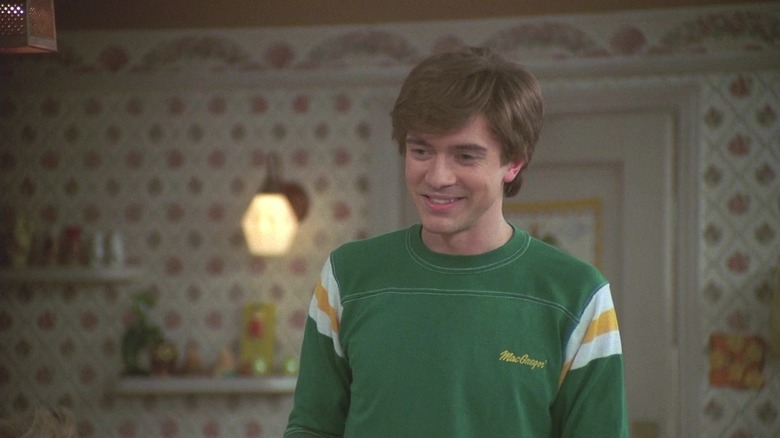 Eric Forman (Topher Grace) stands smiling in a kitchen on That '70s Show