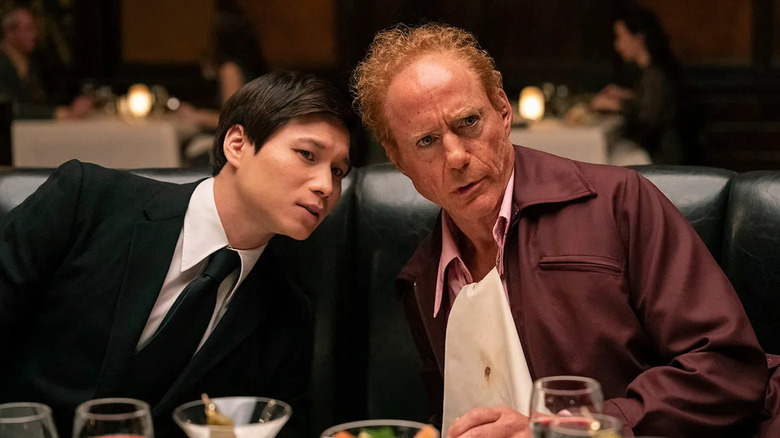 The Captain and Claude leaning close to each other at dinner