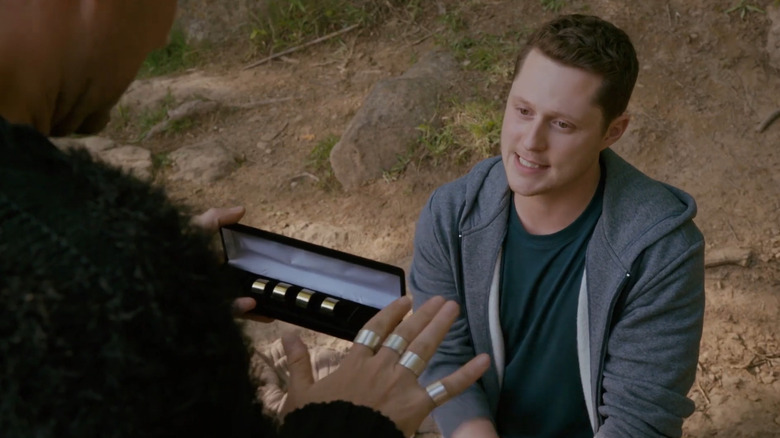 Patrick Brewer (Noah Reid) looking at David Rose's (Daniel Levy) rings in Schitt's Creek