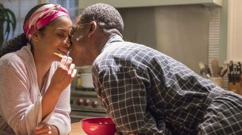 Beth Clarke (Susan Kelechi Watson) smiles as Randall Pearson (Sterling K. Brown) leans over a table to kiss her in This Is Us