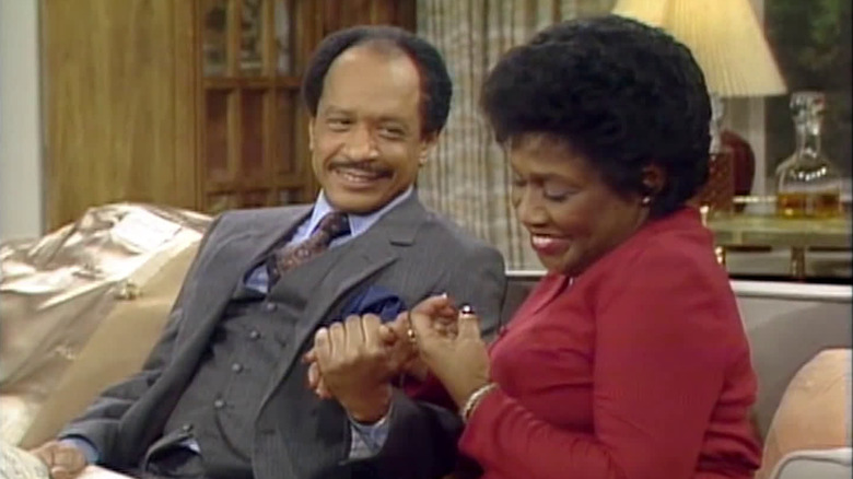 George Jefferson (Sherman Hemsley) and Louise Jefferson (Isabel Sanford) hold hands in The Jeffersons