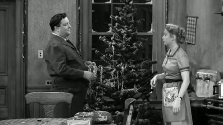 Ralph Kramden (Jackie Gleason) gives a gift to Alice Kramden (Audrey Meadows) in The Honeymooners