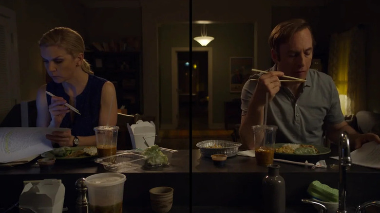Rhea Seehorn as Kim Wexler looking over papers and eating while sitting next to Bob Odenkirk as Jimmy doing the same in Better Call Saul