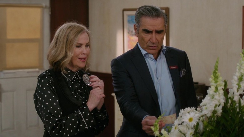Catherine O'Hara and Eugene Levy as Moira and Johnny look at white flowers in Schitt's Creek