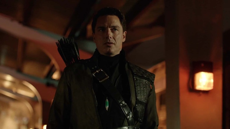 John Barrowman as Malcolm Merlyn, moving in shadow in Arrow.