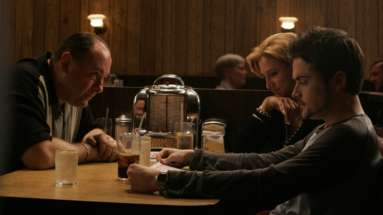 James Gandolfini's Tony Soprano, Edie Falco's Carmela Soprano, and Robert Iler's A.J. Soprano sitting in a restaurant on The Sopranos