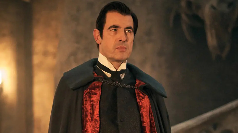 Count Dracula (Claes Bang) glowers while wearing a cape in his castle in Dracula (2020)