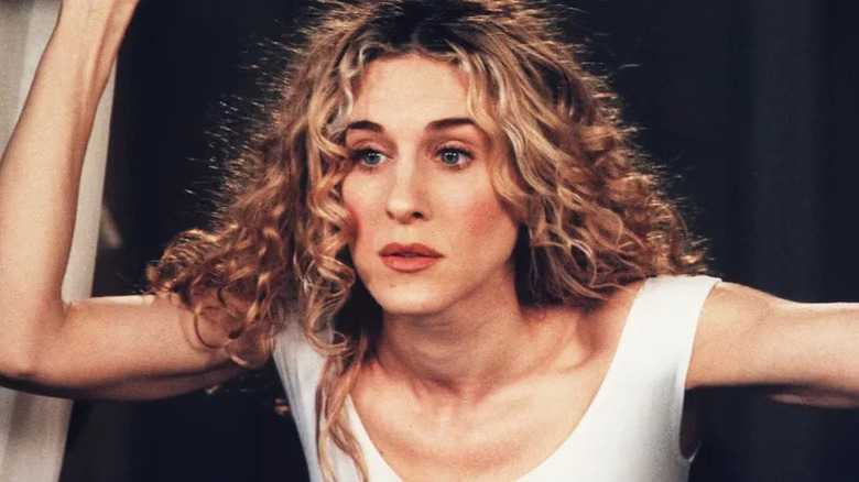 A frazzled Carrie Bradshaw (Sarah Jessica Parker) stands with an arm raised on Sex and the City