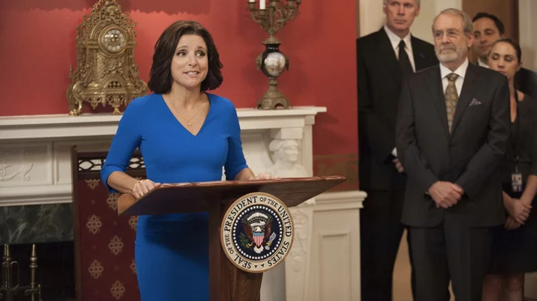 Selina Meyer (Julia Louis-Dreyfus) gives a speech from a podium in an ornate room on Veep