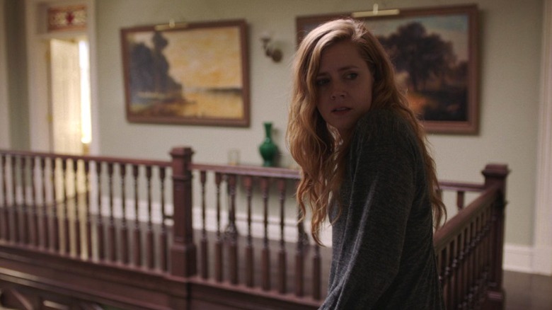 Camille leaning on the balcony and looking back over her shoulder on Sharp Objects S1E1