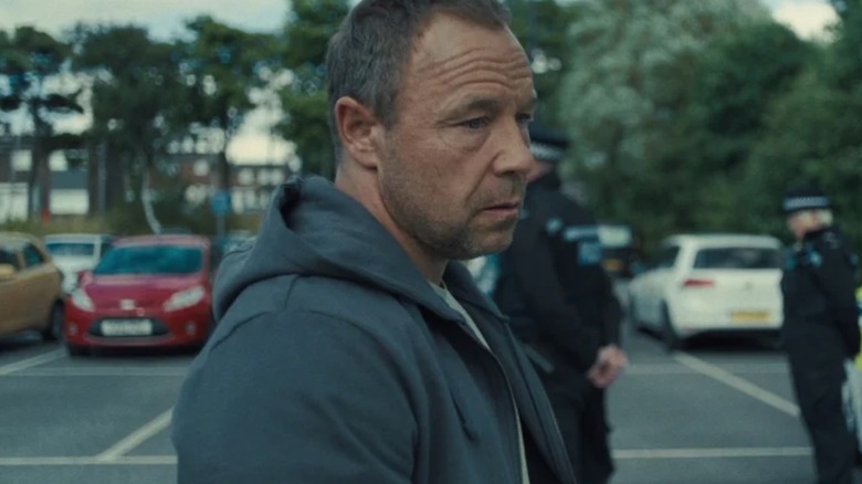 Stephen Graham as Eddie Miller stood in a parking lot on Adolescence