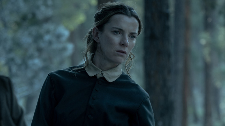 Betty Gilpin as Sara Rowell looking concerned in a forest in American Primeval