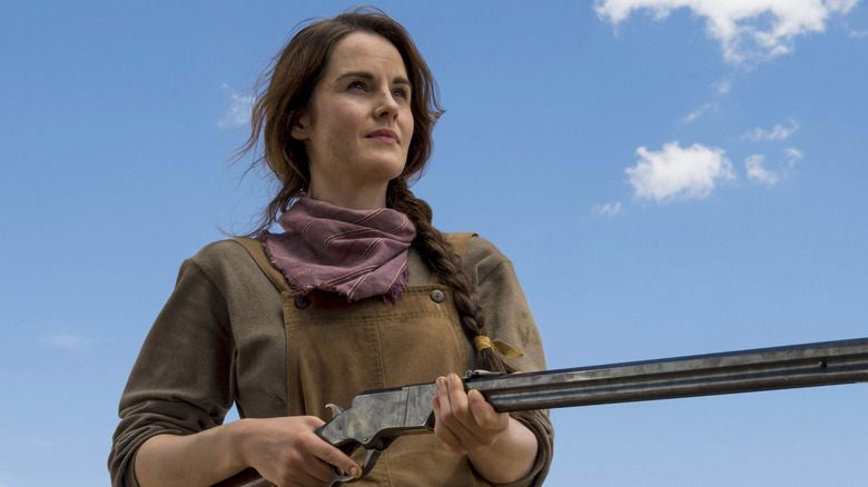 Michelle Dockery as Alice holding a shotgun against a blue sky in Godless