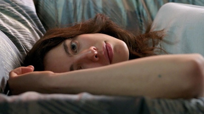 Margaret Qualley as Alex lying on a couch and smiling in Maid