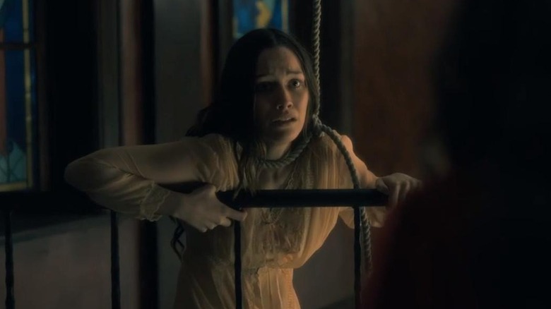 Victoria Pedretti as Nell holding onto a railing with a rope around her neck in The Haunting of Hill House