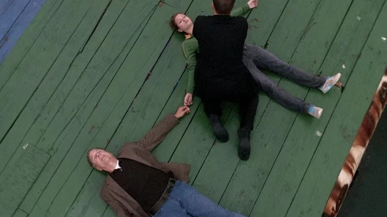 Mark Harmon's Leroy Jethro Gibbs and Cameron Goodman's Maddie Tyler holding hands and lying down while Michael Weatherly's Tony DiNozzo helps them on NCIS
