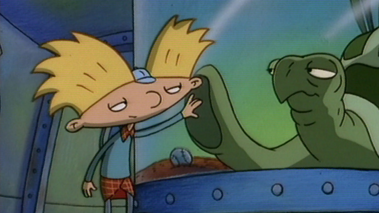 Arnold raises his hand to the fin of a turtle in a glass enclosure in Hey Arnold!.