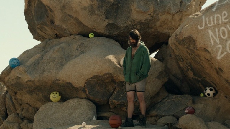 Phil Miller (Will Forte) standing on a rock formation amid balls with scribbled faces on The Last Man on Earth S1E1