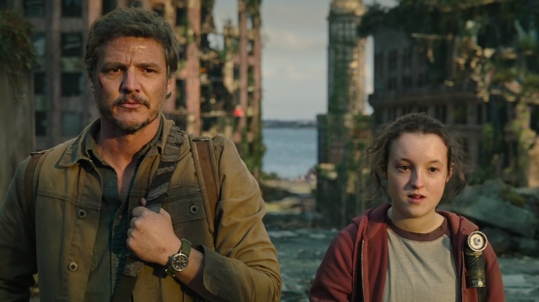 Joel Miller (Pedro Pascal) and Ellie (Bella Ramsey) standing side by side on The Last of Us S1E2