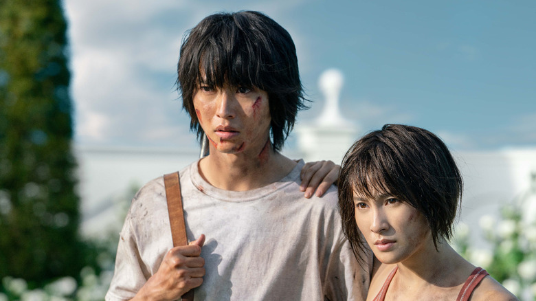 Ryōhei Arisu (Kento Yamazaki) and Yuzuha Usagi (Tao Tsuchiya) stand battered and bloodied together on Alice in Borderland