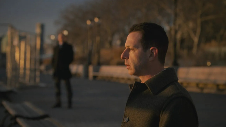 Jeremy Strong as Kendall Roy, sitting on a park bench in shock in Succession.