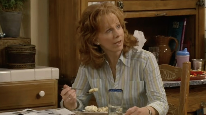 Reba McEntire as Reba sitting at a table with a meal in Reba