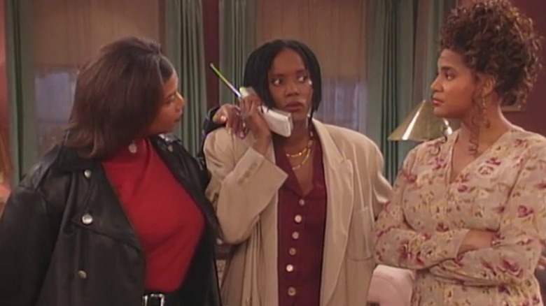Max Shaw speaking on the phone while Khadijah James and Synclaire James stand by and watch her on Living Single S2E10