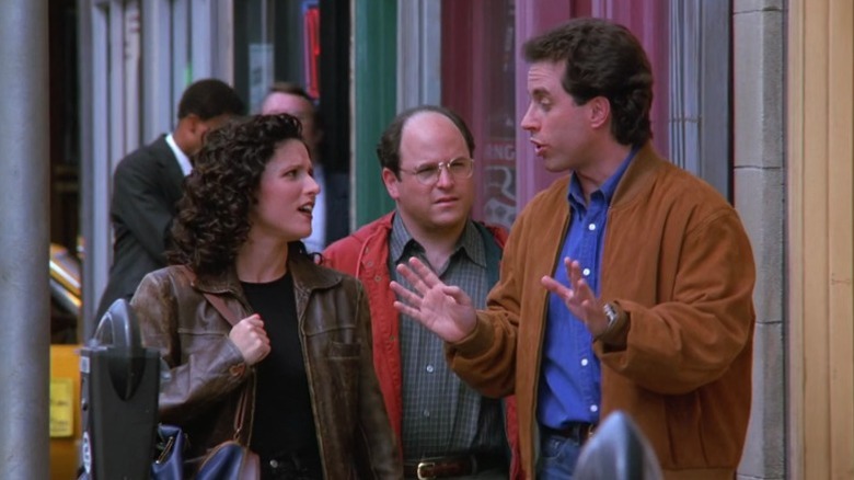 Elaine Benes and George Constanza watching Jerry Seinfeld speak as they walk down the street on Seinfeld S7E6