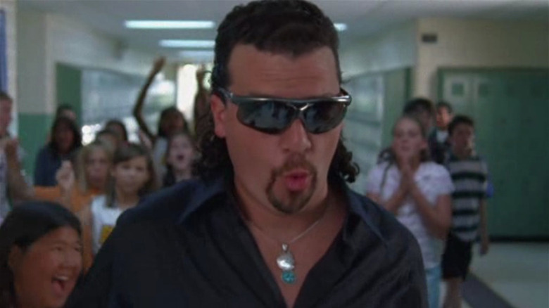 Kenny Powers (Danny McBride) walks down a school hallway with cheering teenagers while making a face on Eastbound & Down