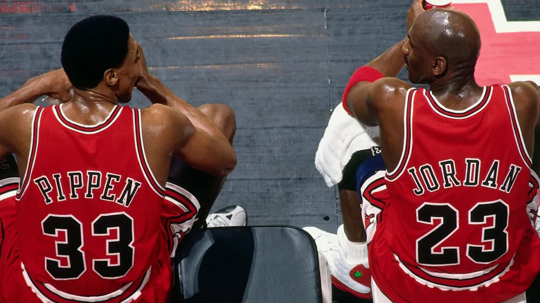 Scottie Pippen and Michael Jordan glance at each other while sitting on the sidelines on The Last Dance