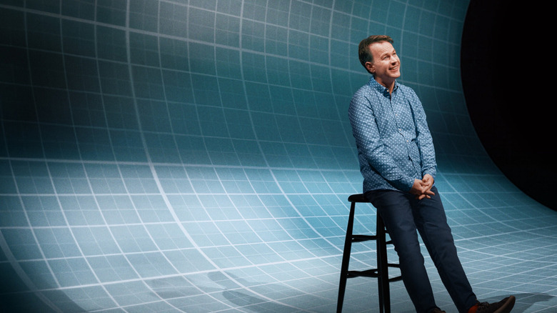 Mike Birbiglia leans back on a stool against a faux pool background in Mike Birbiglia: The Old Man and the Pool (2023)