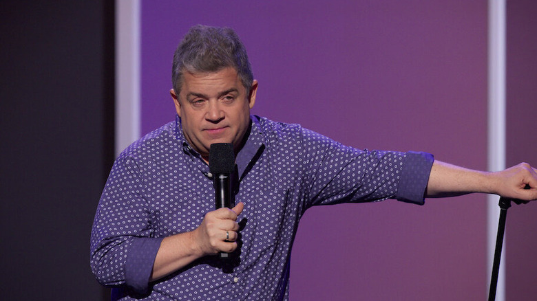 Patton Oswalt leans on a mic stand while holding a mic in Patton Oswalt: I Love Everything (2020)