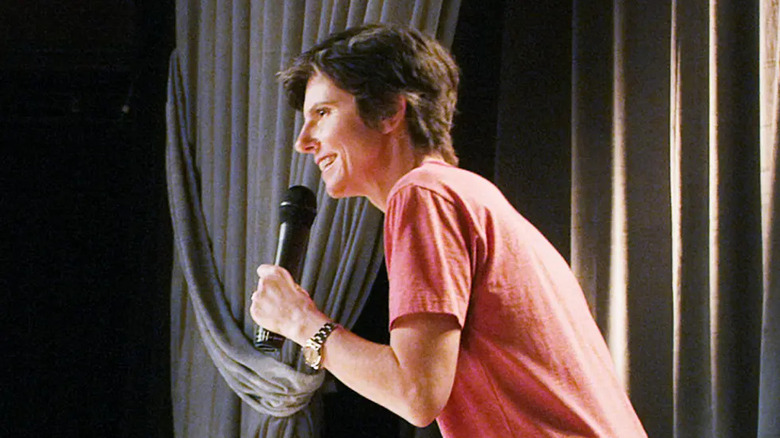 Tig Notaro smiles while holding a microphone in Tig Notaro: Happy to Be Here (2018)