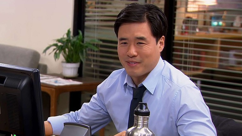 Randall Park as Asian Jim, smiling at Jim's desk in "The Office."