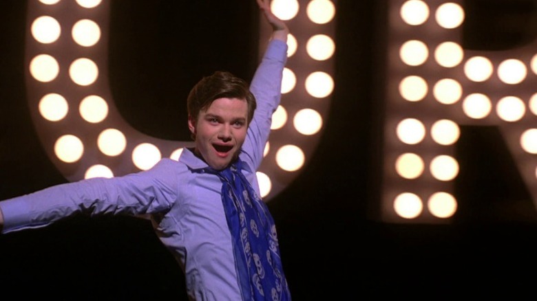 Kurt (Chris Colfer) singing and dancing in front of marquee letters on Glee S1E18