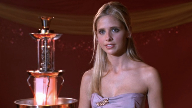 Buffy in prom dress next to punch bowl fountain, smiling