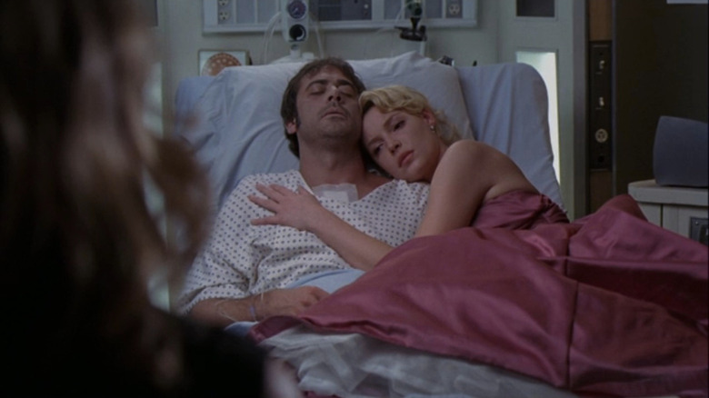 Izzie in pink dress laying beside Denny in hospital bed