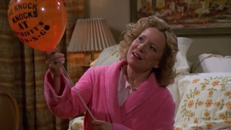 Debra Jo Rupp as Kitty Forman wearing a pink robe and holding a balloon in That 70s Show