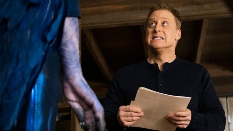 Alan Tudyk as Harry looking up a tall blue creature in Resident Alien