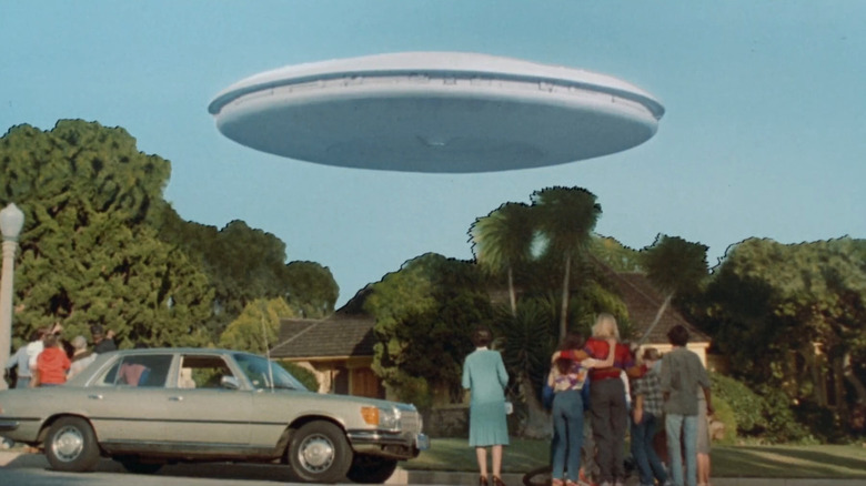People standing in the street with UFO above them in V