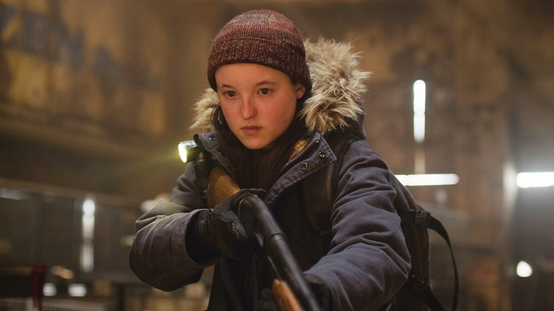 Bella Ramsey as Ellie, holding a shotgun in The Last of Us.