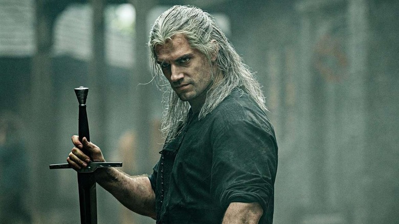 Henry Cavill as Geralt of Rivia, holding a sword in The Witcher.