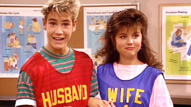Zack Morris stands next to Kelly Kapowski in Saved by the Bell