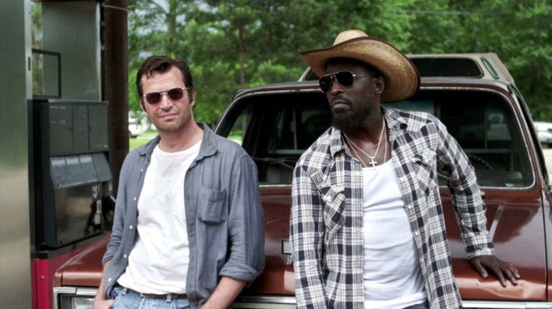 James Purefoy as Hap wearing sunglasses leaning against red car in gas station next to Michael Kenneth Williams as Leonard in sunglasses and cowboy hat in Hap and Leaonard