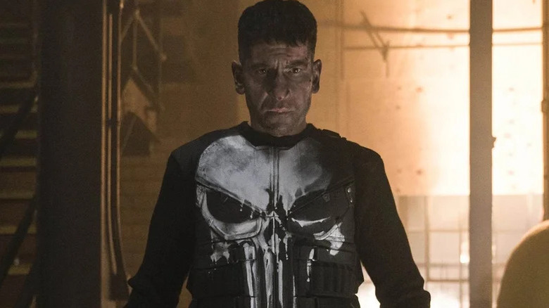 Jon Bernthal as Frank Castle with dirty face and skeleton painted on his vest in The Punisher