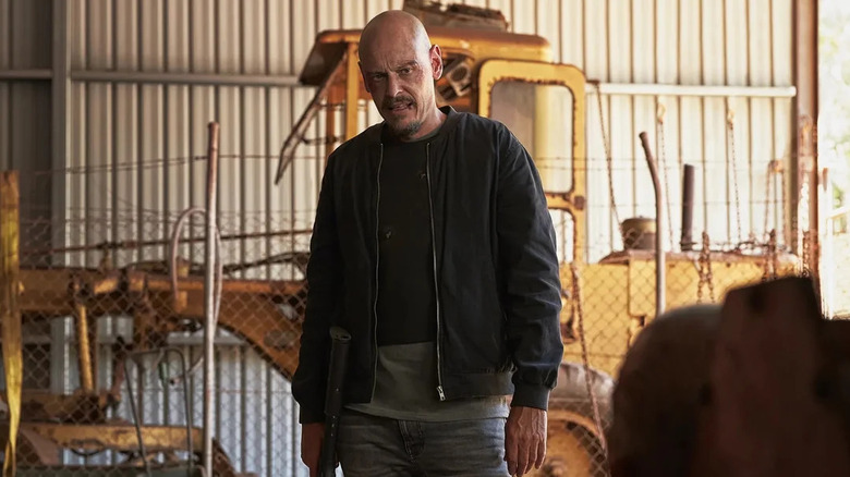 Scott Ryan as Raymond Shoesmith, looking down at a target in Mr. Inbetween.