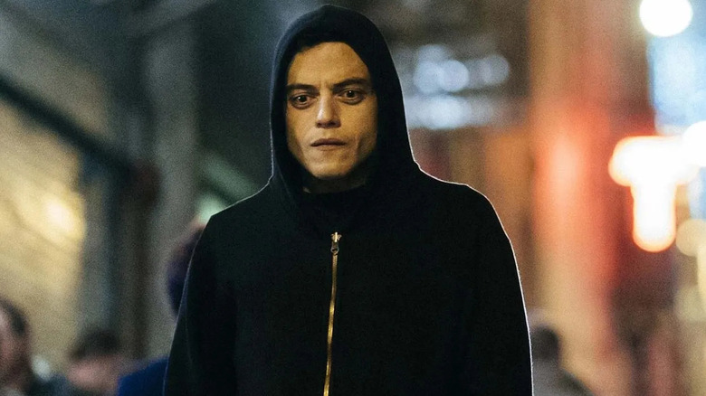 Rami Malek as Elliot Alderson, walking with his hoodie up in Mr. Robot.