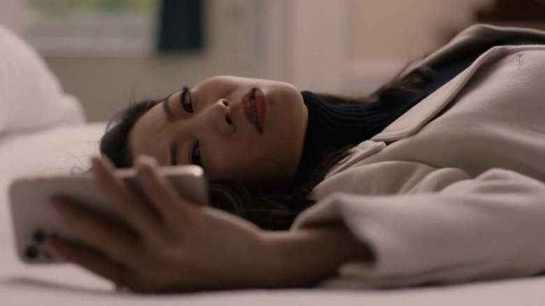 Ingrid looking worriedly at her phone while lying in bed on Partner Track S1E5