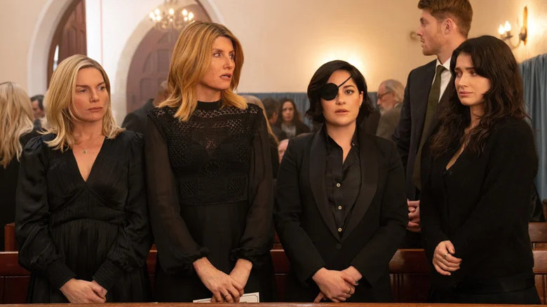 Eva Birthistle as Ursula, Sharon Horgan as Eva, Sarah Greene as Bibi, and Eve Hewson as Becka, all dressed in black at funeral in Bad Sisters